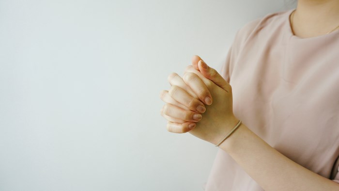 Person praying with hands clasped