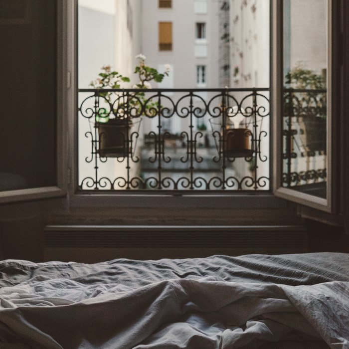 View from a bed through an open window to a balcony in Paris