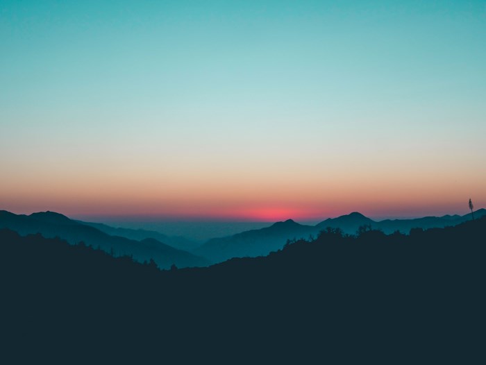 Silhouette of mountains at sunset with teal sky