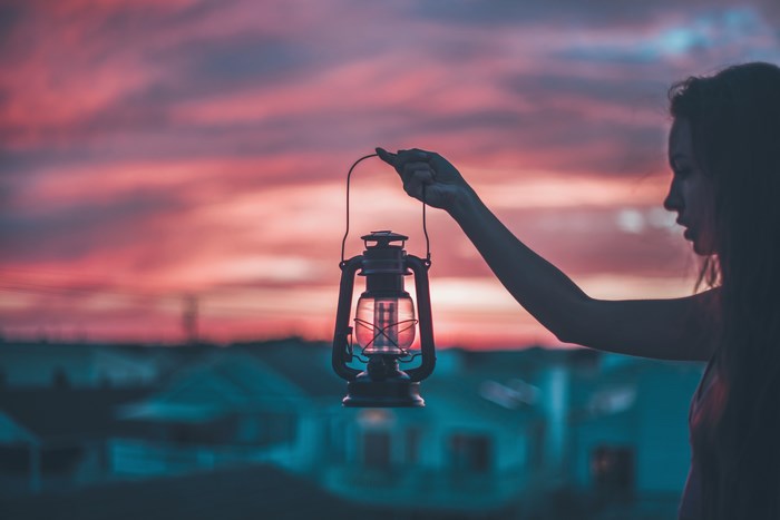 Woman holding a lantern at sunset
