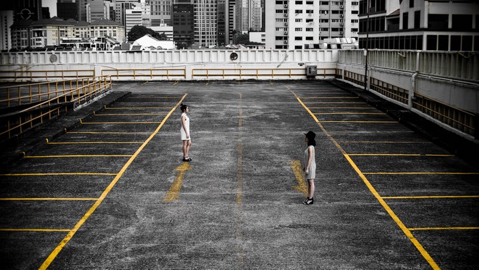 Two women standing in a desaturated parking lot