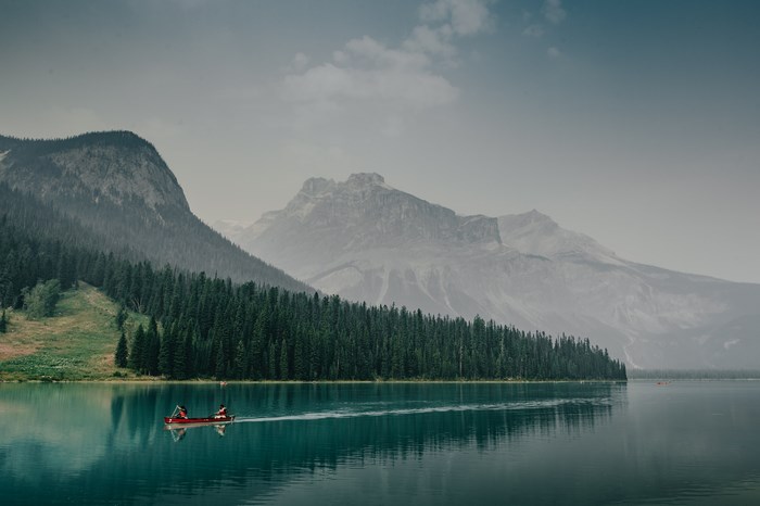 Canoe on a misty lake with mountains and forest