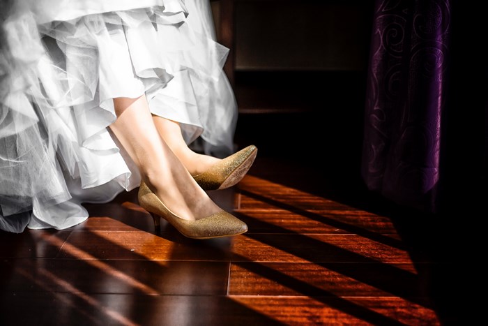 Woman in wedding dress and gold heels on wooden floor