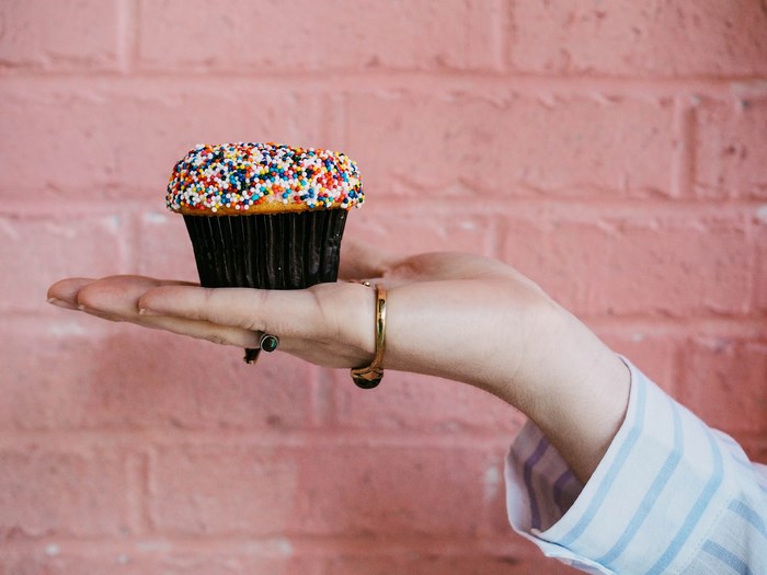Hand holding a cupcake with colorful sprinkles
