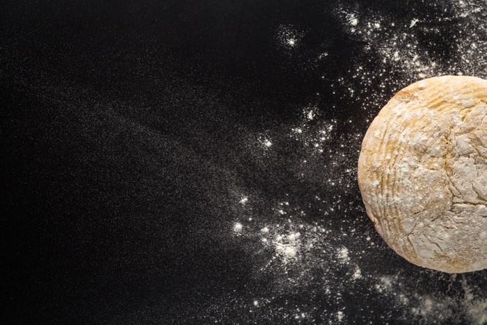 Round bread with flour on a black surface