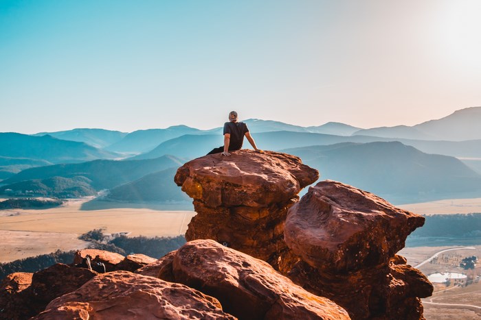 Man sitting on a rock overlooking mountains