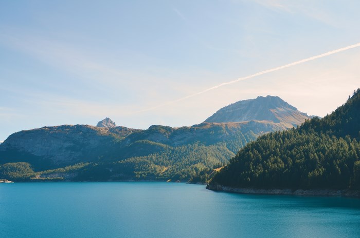Tranquil Lake Surrounded by Forested Hills Under Blue Sky
