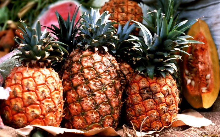 Several pineapples and a cut papaya