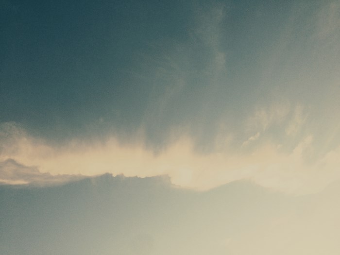 A soft, bright cloud ridge in the blue afternoon sky
