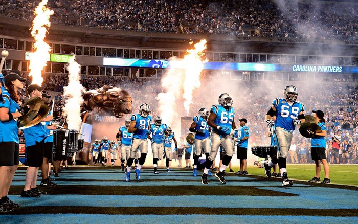 Carolina Panthers football players entering stadium with flames