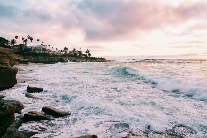 Waves crash on a rocky beach in San Diego at sunset