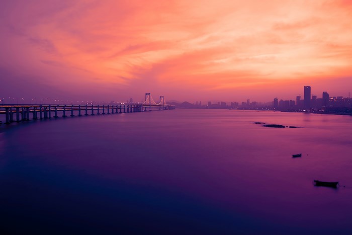 Dalian cityscape with bridge at sunset over water