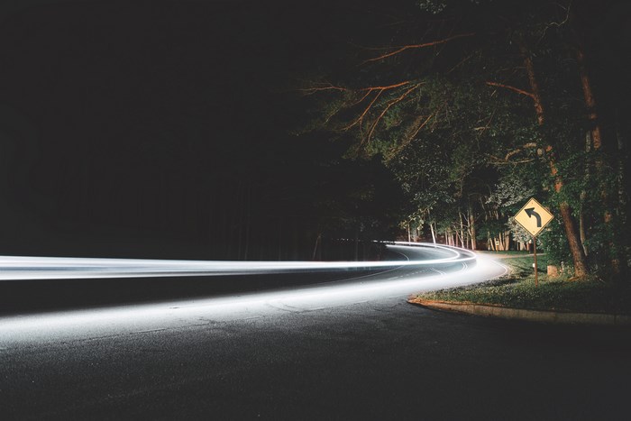 Nighttime Forest Road with Curving Light Trails