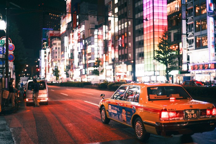 Tokyo street at night with a taxi and neon lights