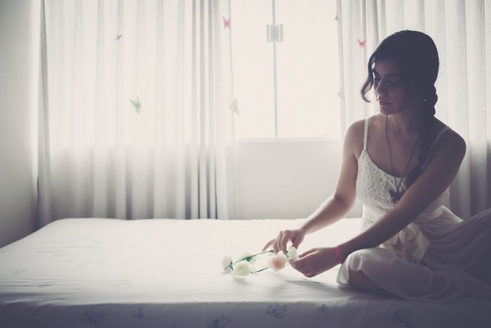 Young woman sitting on a bed with flowers