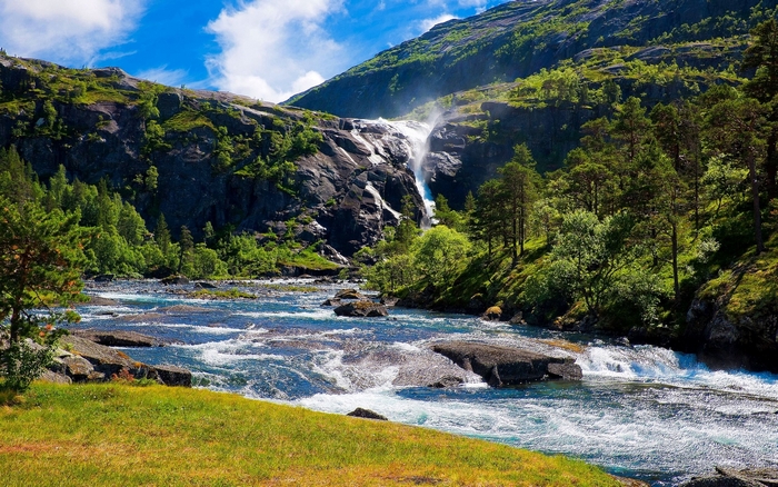 Waterfall cascading into a river in a mountainous landscape