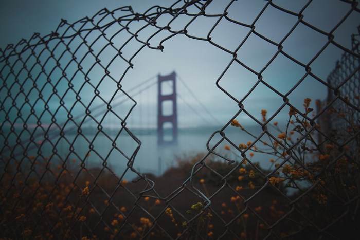 Golden Gate Bridge through a broken chain link fence