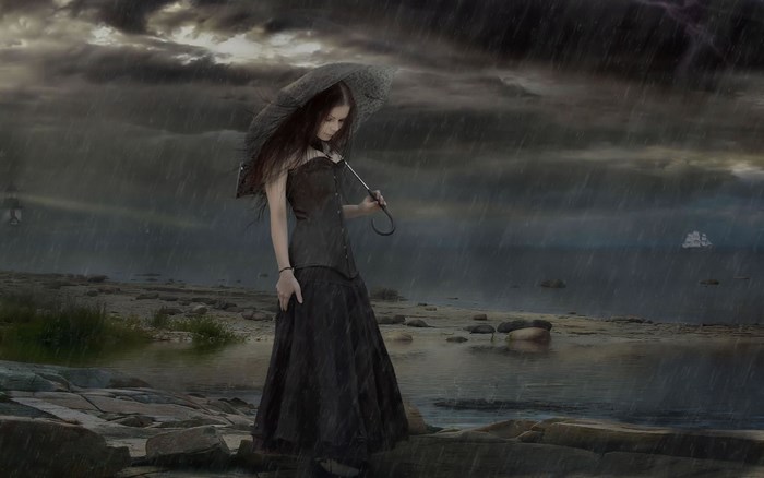 Woman with umbrella in the rain on a rocky shore