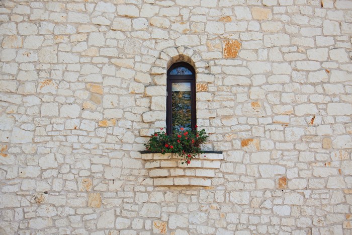 Arched window with flowers on a stone wall