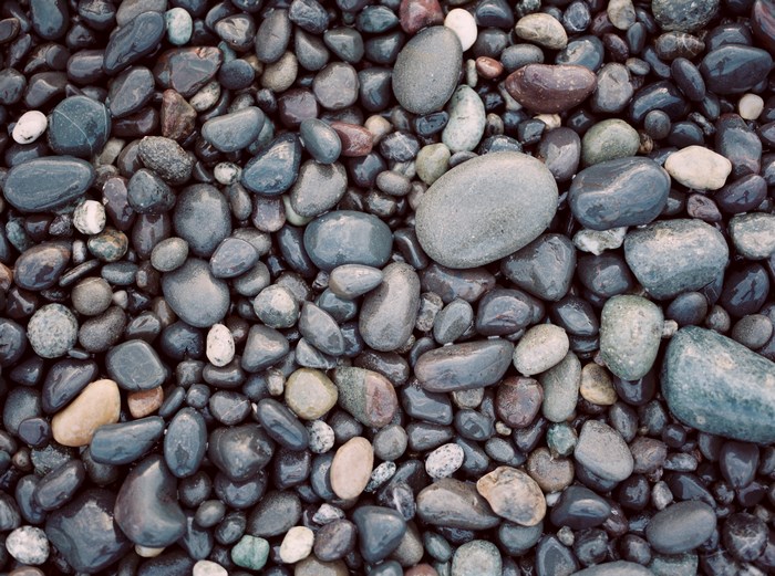 Close-up texture of wet, smooth pebbles on a beach