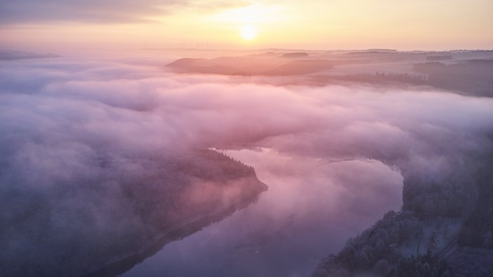 Sunrise over a misty lake and forest in Luxembourg