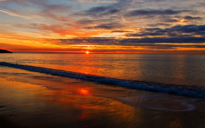 Sunset over the ocean with waves on the beach