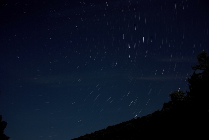 Star trails in the night sky over a silhouetted landscape