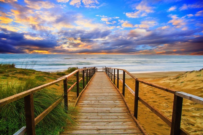 Wooden boardwalk to the beach at sunset