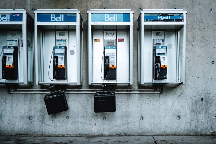 Four Bell payphones mounted on a concrete wall