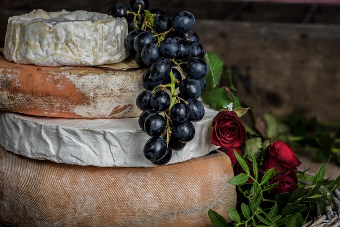 Stack of French cheeses with grapes and roses