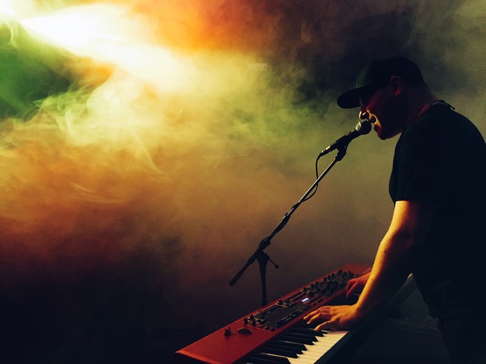 Musician playing a red keyboard and singing into a microphone