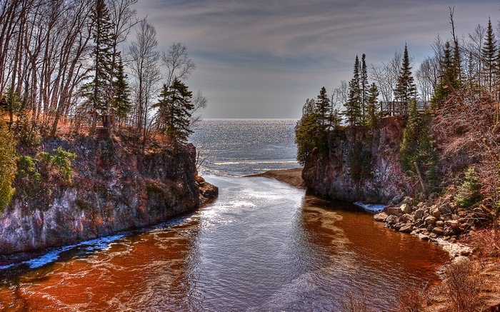 River flowing into a large body of water between rocky cliffs