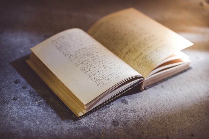 Open book with handwritten script on concrete
