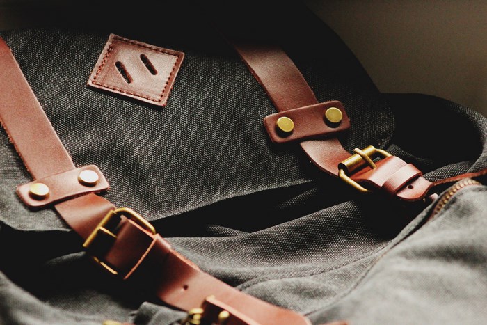 Close-up of a dark canvas bag with leather straps and buckles