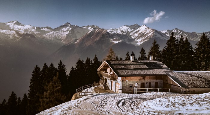 Wooden cabin in snowy mountains with pine forest