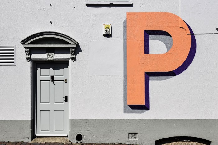 Large painted letter P on a white wall next to a door
