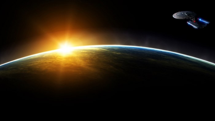 Star Trek spaceship orbits Earth at sunrise