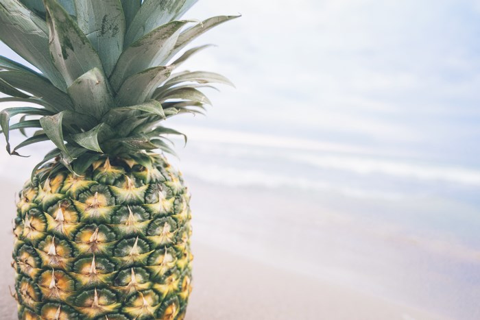 Pineapple on a sandy beach with ocean waves