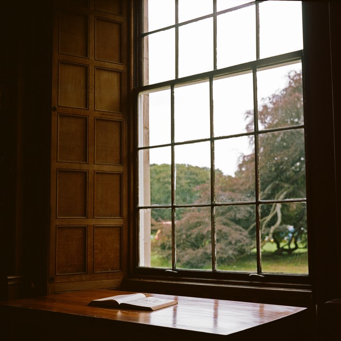 Open book on a wooden windowsill looking out a window