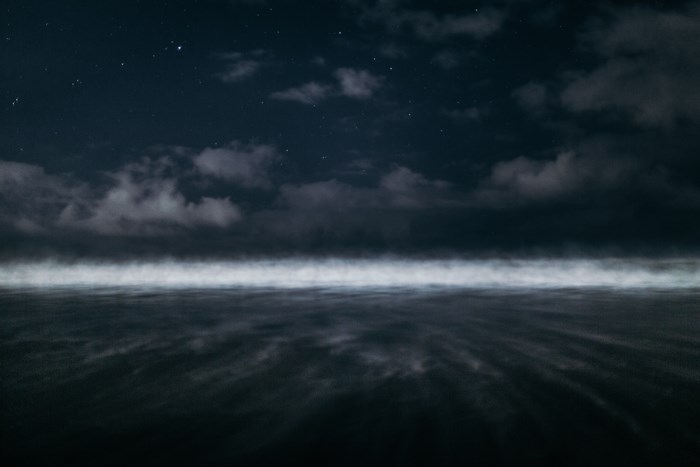Night sky over a misty ocean horizon