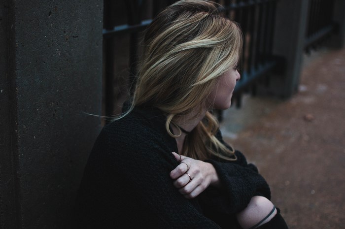 Woman sitting by a dark wall