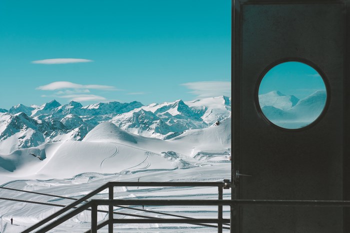 Snowy mountains seen through a round window in a door