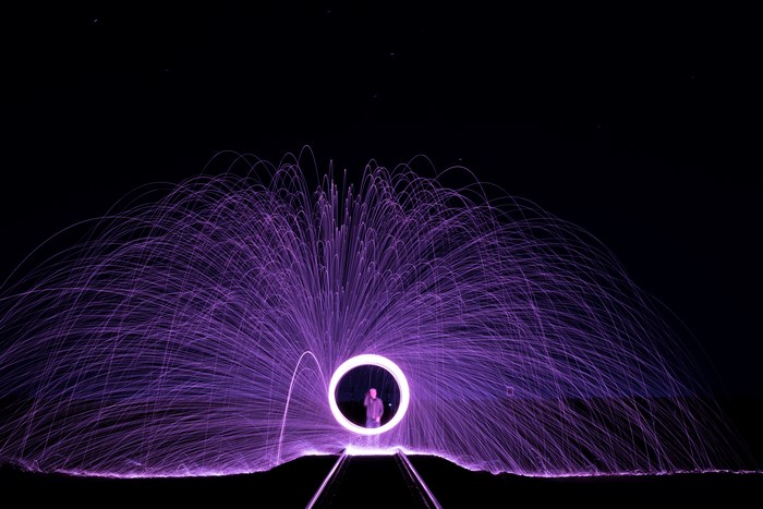 Man in a circle of purple light painting with fire