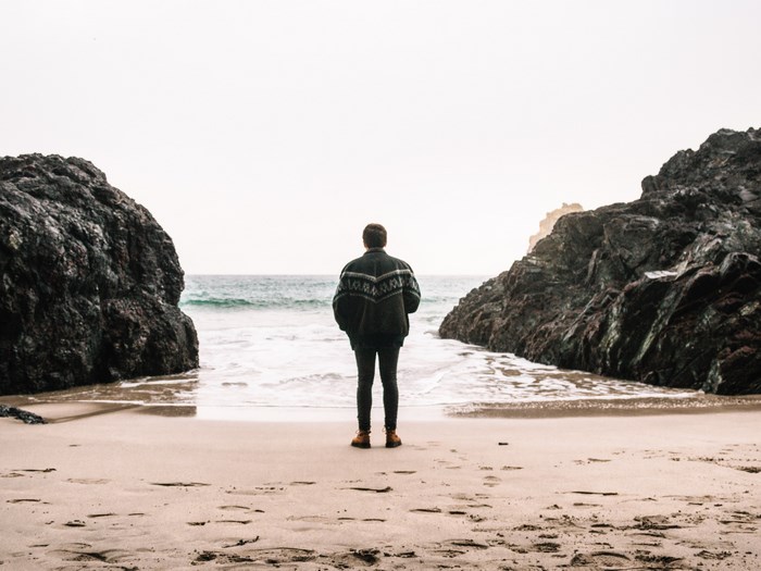 Man standing on a beach between rocks in Cornwall