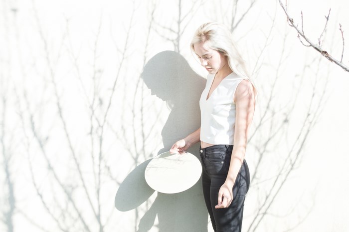 Young blonde woman holding a plate with tree shadows