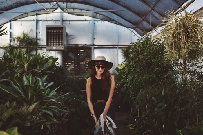 Woman in hat and sunglasses in a greenhouse