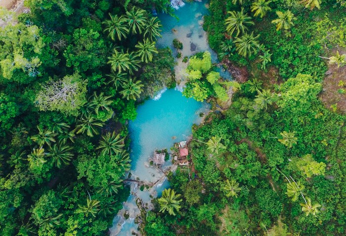 Aerial view of a turquoise lagoon surrounded by a lush forest
