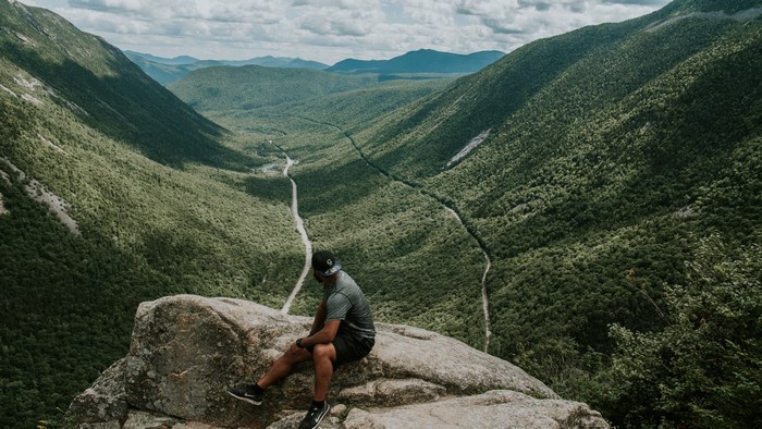Man sitting on a rock overlooking a valley