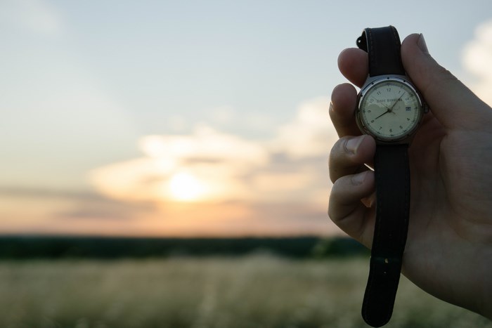 Person holding a watch at sunset