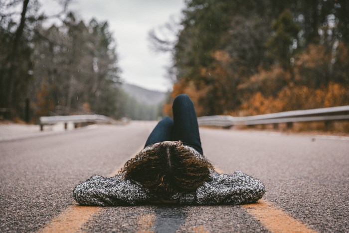 Woman lying on a road in a forest